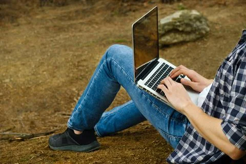 Man sitting on ground at forest and working on laptop Stock Photos