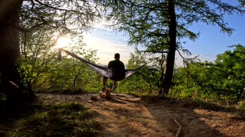 Man sitting on hammock eating burger enjoying sunset Stock Footage 253166909