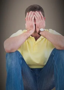 Man sitting with hands on face against brown background Stock Photos