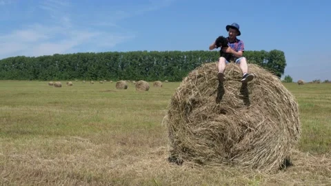 A man is sitting on a haystack with a dog. Stock Footage 135496650