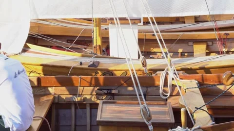 А man sitting with his back is preparing an old wooden sailing yacht Stock Footage 255438974