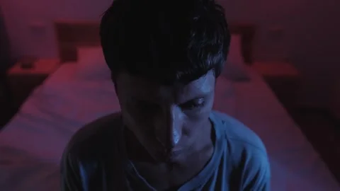 Man sitting on his bed overwhelmed by racing thoughts and uncertainty 스톡 동영상 347301455