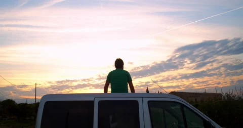 Man sitting in his caper van during a sunset. Travel and adventure concept Stock Footage 195125931