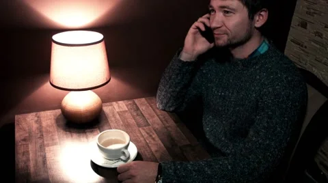 Man sitting at his desk talking on the phone and drinking coffee Stock Footage 56250943