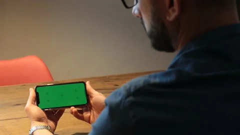 Man sitting holding and looking at smartphone with green screen. Stock Footage 170953465