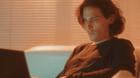 Man Sitting at Home and Using Laptop in the Evening Stock Footage 257519970