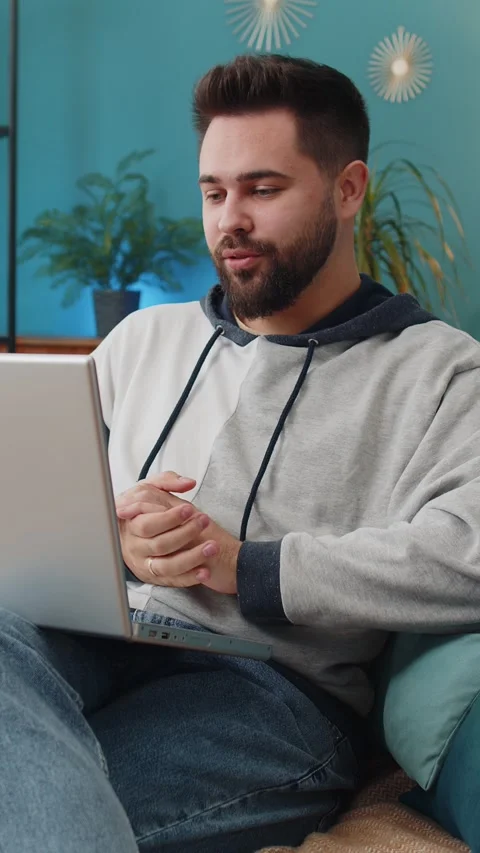Man sitting on home couch, looking at camera, making video conference call with Stock Footage 347055554