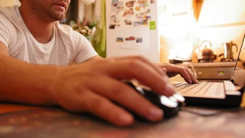 Man sitting at home at the kitchen table, man uses computer, looks at monitor Stock-Footage 120092161