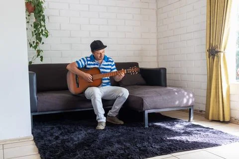 A man sitting at home practicing the guitar Stock-Fotos