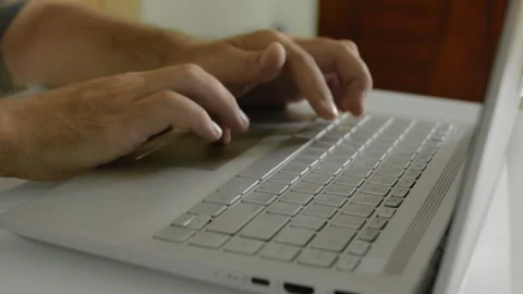 A man is sitting at home at a table and surfing the Internet at a laptop Vídeo Stock 145627001