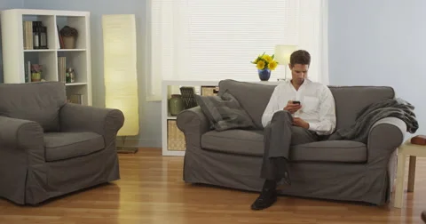 Man sitting at home using smartphone on couch Video stock 42688069