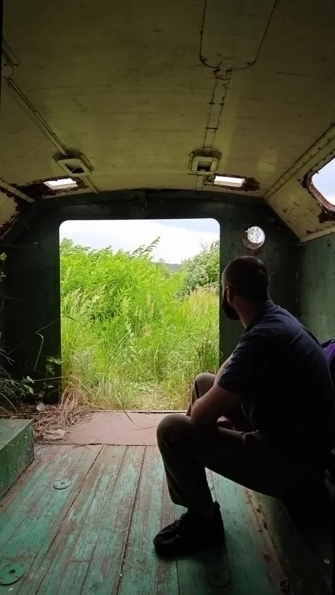Man Sitting Inside Abandoned Military Wagon Looking Outside Stock Footage 339621571