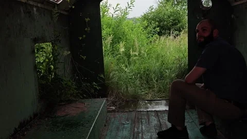 Man Sitting Inside Abandoned Trailer Looking at Heavy Rain Storm Stock Footage 339589999