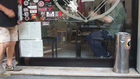 Man sitting inside a café viewed through a glass window with reflection and Stock Footage 314706719