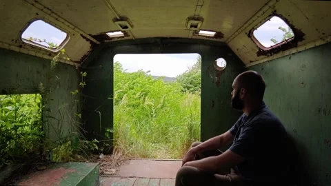 Man Sitting Inside Green Abandoned Trailer Looking Out Open Door Stock-Footage 339589908