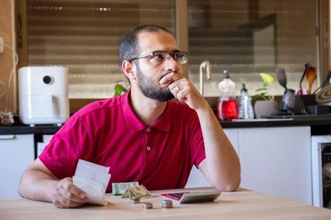 Man sitting in the kitchen and calculating the costs of living feeling frus.. Stock Photos