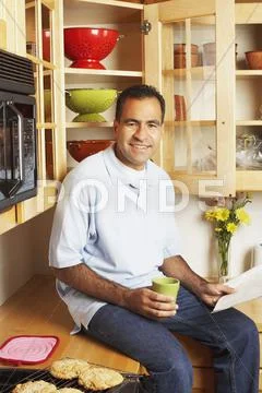 Man sitting on kitchen counter Stock Photos