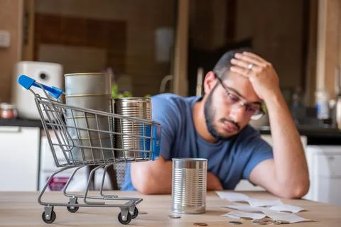 Man sitting in the kitchen holding receipt feeling frustrated due inflation.. Stock Photos