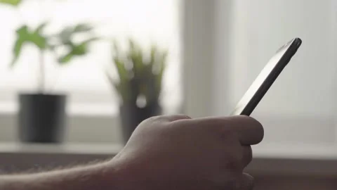 A Man Sitting in the Kitchen Looks through Messages on a Smartphone Stock Footage 152529638