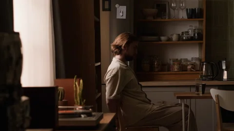Man Sitting at Kitchen Table Drinking Coffee during Morning Routine Stock Footage 345518543