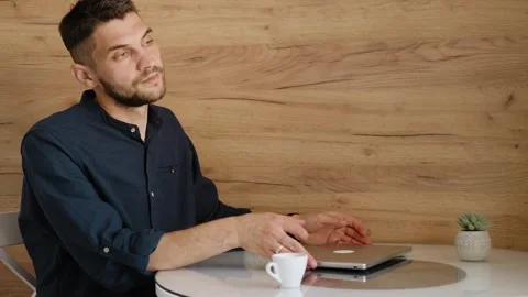 Man sitting at kitchen table looks at his watch and prepares to start work on Stock Footage 342544542