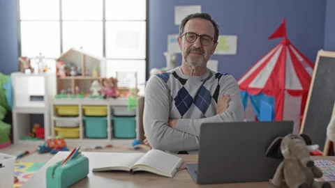 Man sitting at laptop smiling with arms crossed in school classroom with to.. Stock Footage 337444987