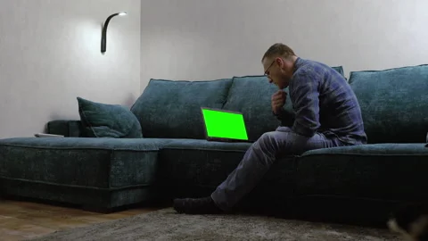 Man sitting on a large comfortable sofa with his laptop Stock Footage 158932273