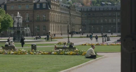 Man sitting on lawn in thought in front of large statue of Stuttgart Stock Footage 195319294