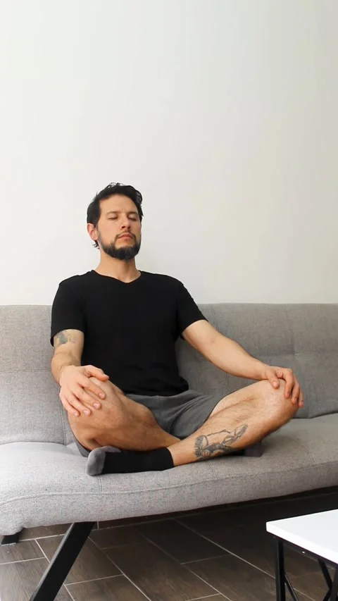 Man sitting at the left side of a couch with his legs crossed Vídeo Stock 340583543
