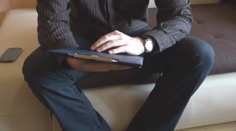 Man sitting on living room couch open clipboard with working papers, reading Stock Footage 45383493