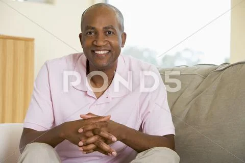 Man sitting in living room smiling Stock-Fotos