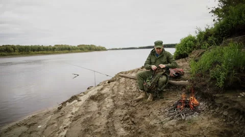 Man is sitting on a log and looking for something in a bag Video stock 93540430