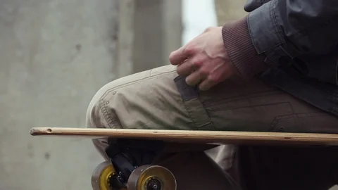 Man sitting on longboard and checking smartphone. Vídeo Stock 90527172