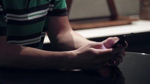 Man in a sitting is looking for something in the phone Stock Footage 76983619