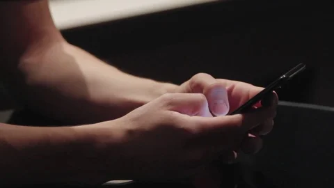 Man in a sitting is looking for something in the phone Stock Footage 76983701