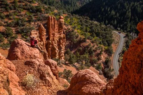 Man sitting looking toward camera atop red rock formations of Southern Utah. Stock Photos