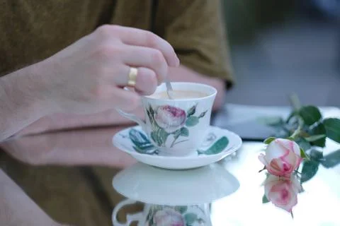 A man is sitting at a mirror table with a cup of cappuccino Stock Photos