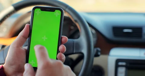 Man sitting at modern car using smartphone with green screen chroma key surfing Stock Footage 165150061