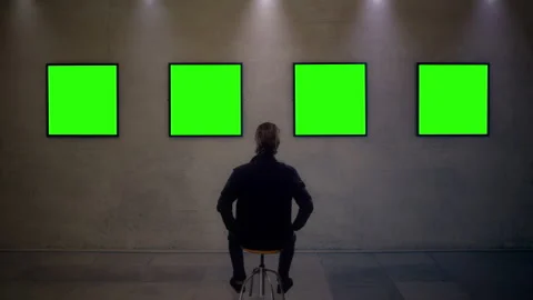Man Sitting in Modern Gallery Viewing Green Screen Frames 库存影片 341670994