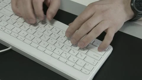 Man sitting in a modern office typing on a white computer keyboard Stock Footage 130600398