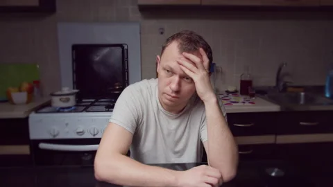 A man sitting motionless in the kitchen in the evening, depressed, crisis Stock Footage 135307674
