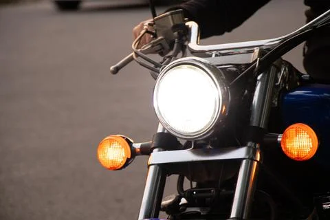 Man sitting on motorcycle, front view of round headlight and orange turn sign Stock Photos