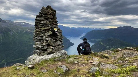 Man sitting on mountain summit overlooking norwegi Stock Footage 337365028