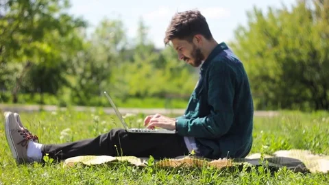 A Man Sitting in a Nature Using His Laptop Stock Footage 76487945