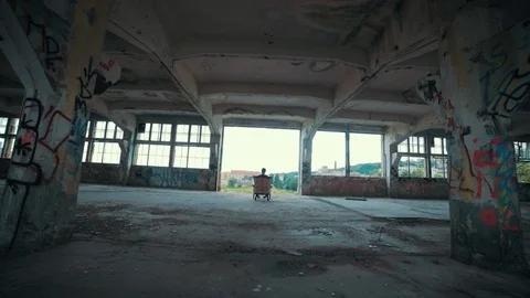 Man sitting next to the abandoned building and looking to the city, steadycam Stock Footage 104619291