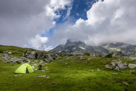 Man sitting next to his tent in the mountain after a hike at Rila mountain in Stock Photos