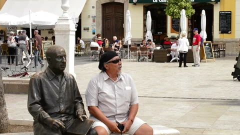 Man sitting next to Pablo Picasso bronze statue in Malaga Spain square Stock Footage 340274448