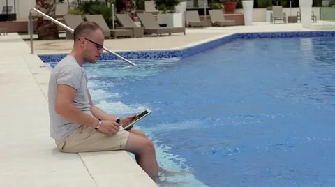 Man sitting next to the pool with tablet and smartphone Stock Footage 53490418