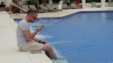 Man sitting next to the pool with tablet and smartphone Stock Footage 53606680