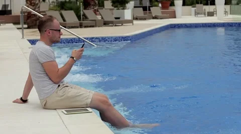 Man sitting next to the pool with tablet and smartphone Stock Footage 53808952